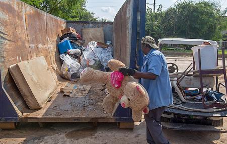 Workers throw away debris and ruined possessions from a public housing project in Texas.